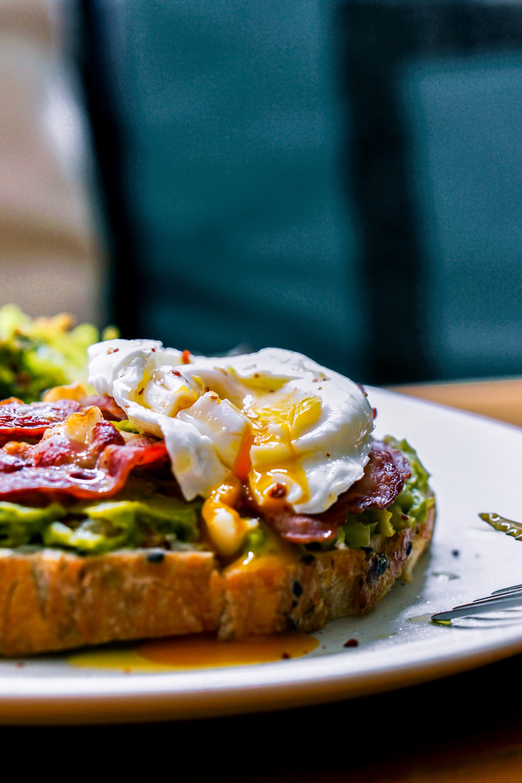 Zoomed in plate of avocado and toast with bacon and poached egg